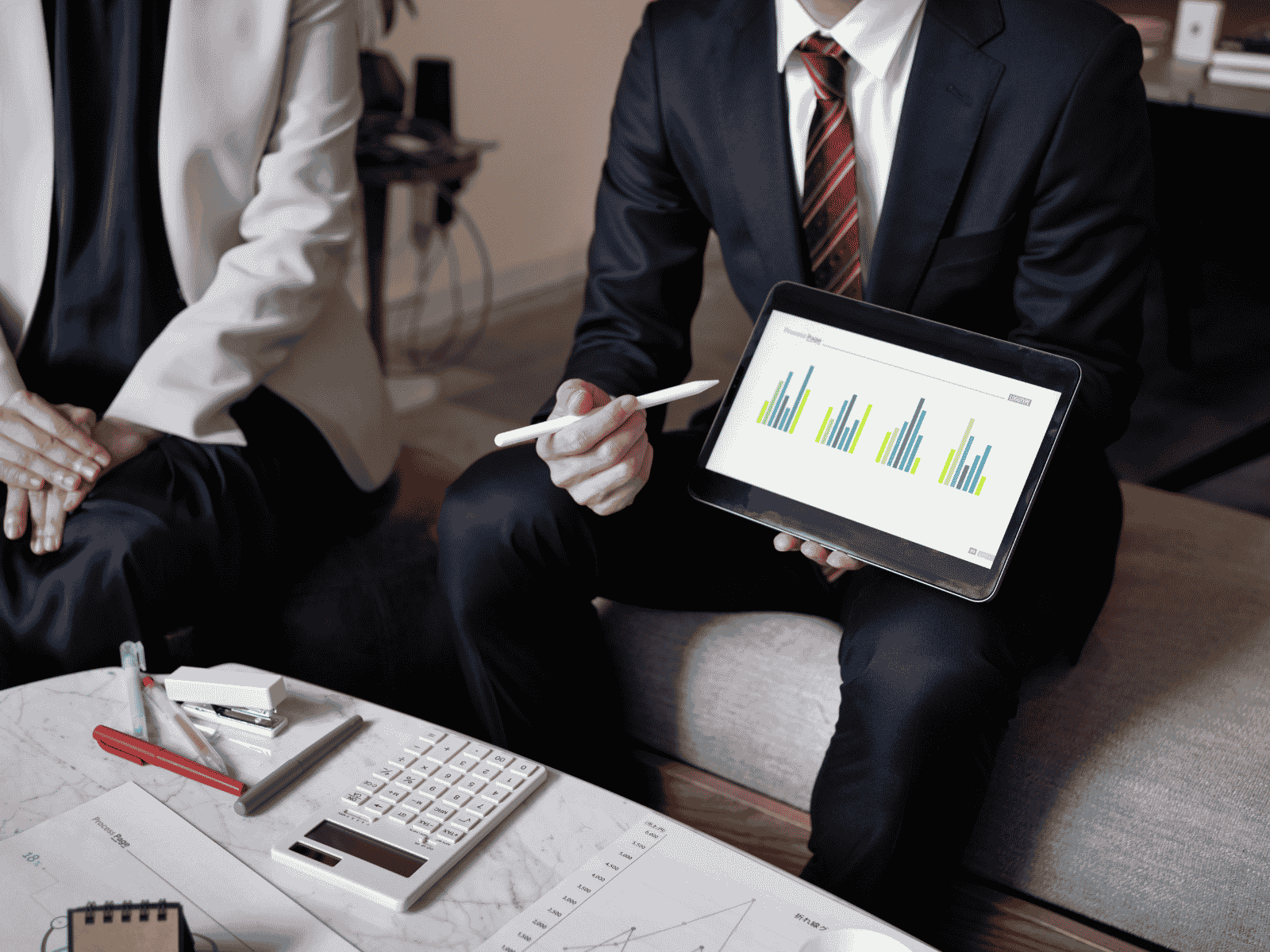 Manager presenting growth data on a tablet to an investor, demonstrating investment readiness and execution