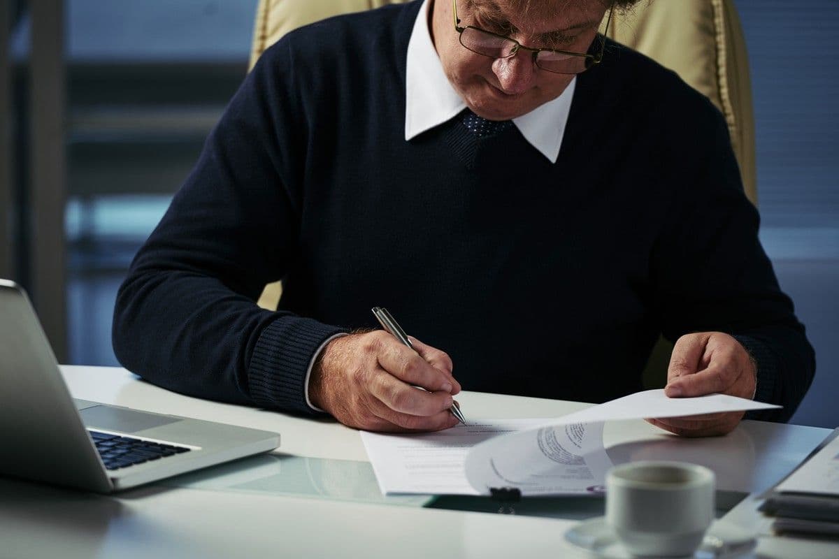 Senior investor reviewing and signing an investment memo before an investment committee decision