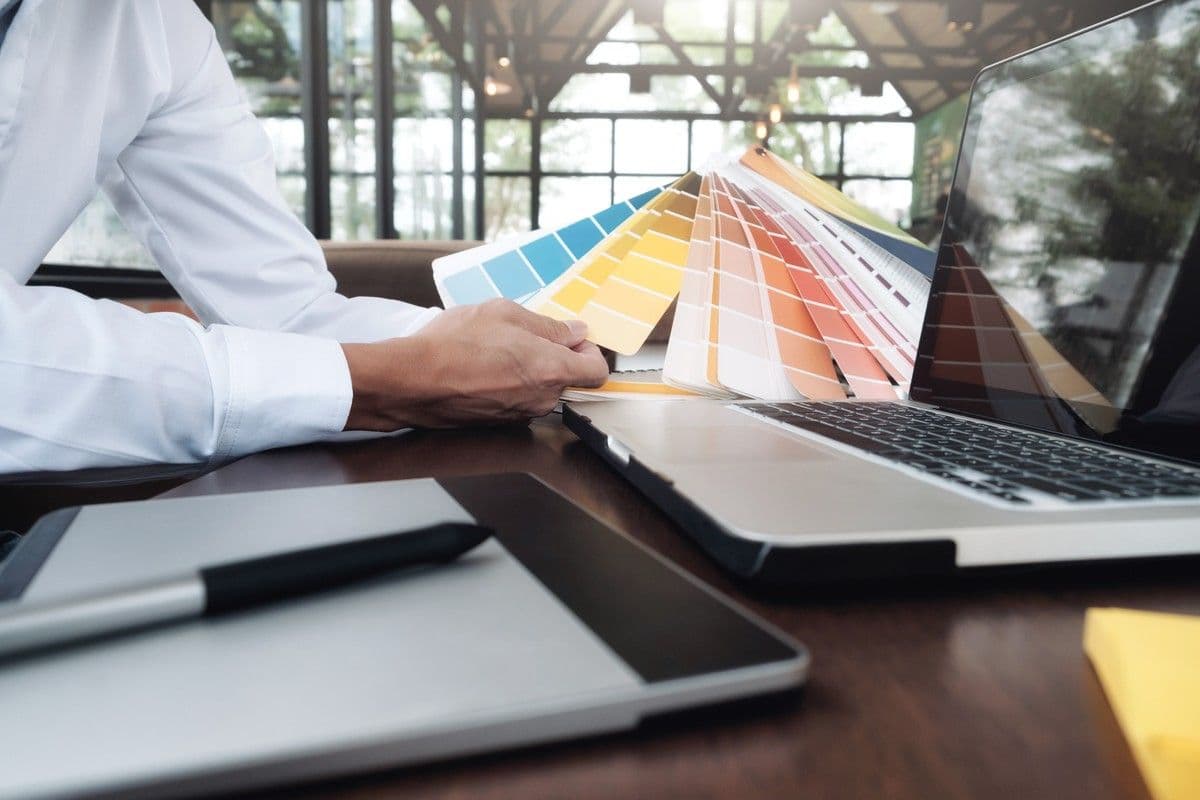 Brand designer comparing color swatches while documenting a bilingual branding system for investors